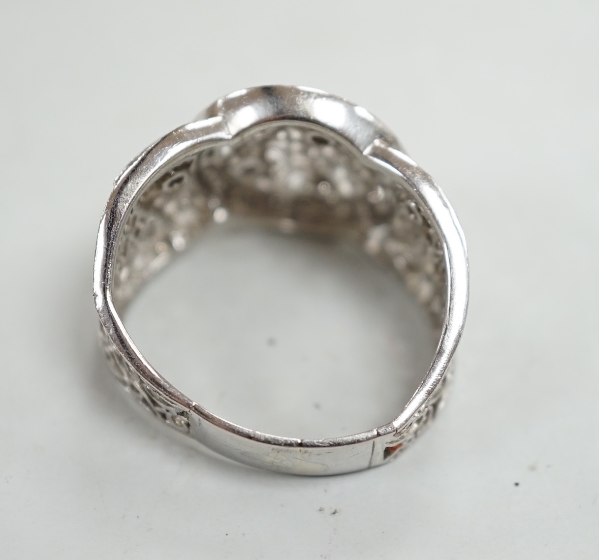 A pierced white metal and diamond chip set diamond ring, with scrolling decoration, size Q/R, gross weight 10.4 grams.